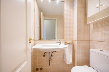 Bathroom with large sink for hand washing and light sand tile and built-in wall mirror