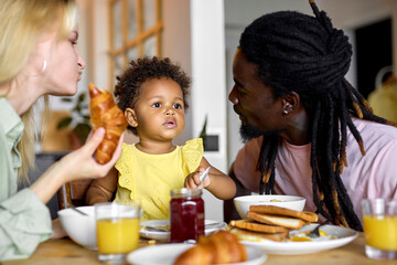 Beautiful multi-ethnic caucasian european black family having breakfast at home in bright cozy kitchen. Breakfast, parenthood, family concept. leisure, free time on holidays, weekends