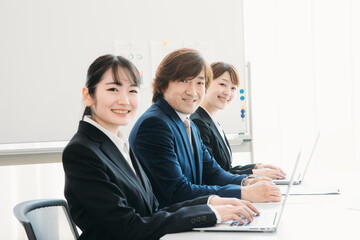 Fototapeta premium 会議室にいるスーツ姿の男女（カメラ目線・笑顔） 