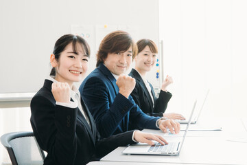 Fototapeta premium 会議室にいるスーツ姿の男女（カメラ目線・ガッツポーズ） 