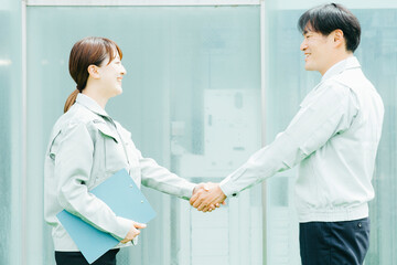 握手する作業着姿の男女
