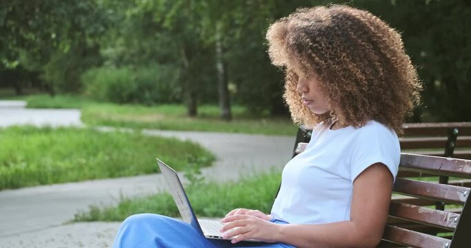 Pensive creative mixed race business female planning work use laptop pc relaxing on bench outdoor park. Wistful female student enjoying online distance e learning remotely education on computer pc