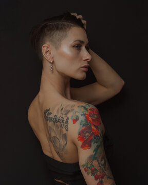 girl with a tattoo on the shoulder and back on a black background in the studio