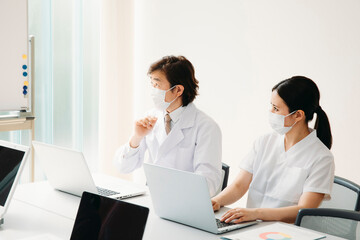 Fototapeta premium 会議する白衣姿の男女（マスク） 