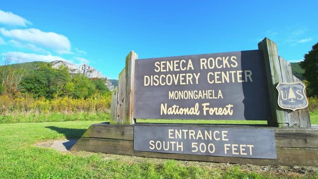 Sign for Seneca Rocks at Monongahela national forest in colorful fall autumn with golden yellow foliage by meadow grass on sunny season weather