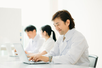 白衣を着た男性（パソコン・笑顔）
