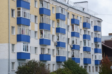 The facade of the old brick house is painted blue and white, balconies and modern windows, a beautiful bright street view. Reconstruction, restoration, improvement, renovation of the housing stock.