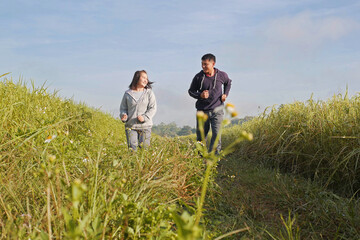 Asian couple jogging together, outdoor morning run in nature trail organic rice paddy field. Healthy lifestyles and sustainability concepts.