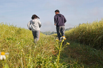 Rear view Asian couple jogging together, outdoor morning run in nature trail organic rice paddy field. Healthy lifestyles and sustainability concepts.