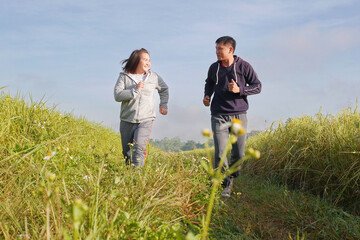 Asian couple jogging together, outdoor morning run in nature trail organic rice paddy field. Healthy lifestyles and sustainability concepts.
