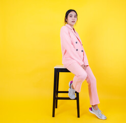 Naughty Asian girl on pink pastel jacket and pants sit leisurely on high chair posing model...