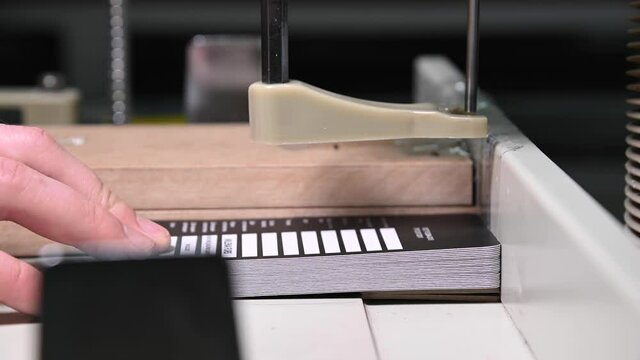 Close-up of a man making a puncture on printed and cut labels for products in manufacturing