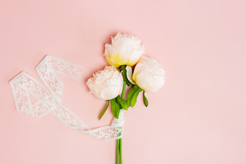 A bouquet of white roses with ribbon on pink background.