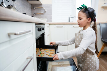 Portrait of child girl. She cuted cookies from dough with shape cutter and puted on baking sheet.