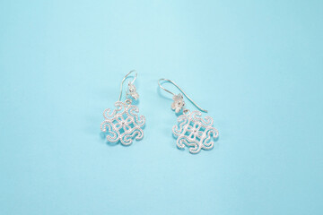 Tribal silver earrings on pastel blue background