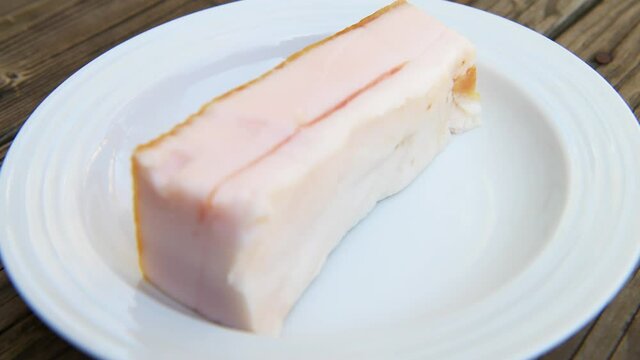 Macro closeup rack focus of traditional salted pork belly fat food for making sandwiches from slices of the lard as traditional Russian cuisine on plate