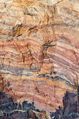 A fragment of a natural colorful mineral quartzite in close-up. The pattern of a mountain stone with a textured surface.
