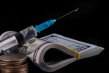 Disposable syringe and American currency on black background