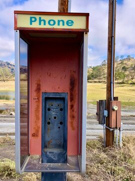 an old red telephone box, a sign of the times, stands as a monument to the demise of older technology due to the rapid development of new technology 