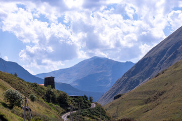 A watch tower next to a road leading to the village of Juta in the Greater Caucasus Mountain Range in Georgia, Kazbegi Region. Electricity lines on teh side. Hiking trail Juta-Roshka. Wanderlust