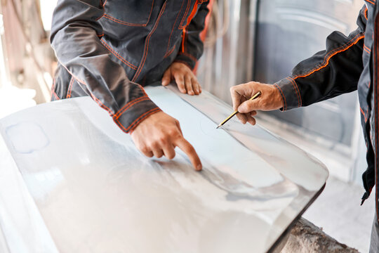 Two workers discuss the execution of the work of Repairing car body, Application putty close up. The mechanic repair the car. Work after the accident by working sanding primer before painting.