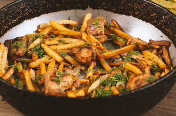 Fried Meat with fried halves of potatoes in a skillet