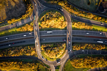 Aerial view directly above a busy UK motorway with overpass roundabout junction - obrazy, fototapety, plakaty