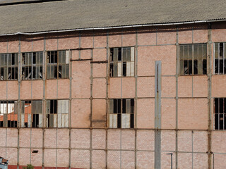 Old factory with dilapidated brick wall with broken windows.