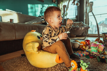 Little boy eating chocolate pudding and watching tv. Cute happy boy smeared with chocolate around his mouth. Child concept, home concept