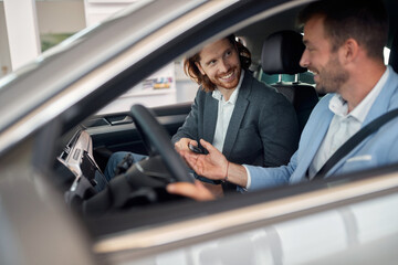 Smiling  car dealer showing  car to customer