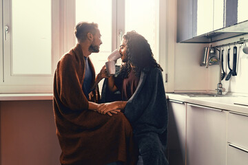 A gay male couple drinks milk in the morning. Two homosexuals hug each other under a blanket. - obrazy, fototapety, plakaty