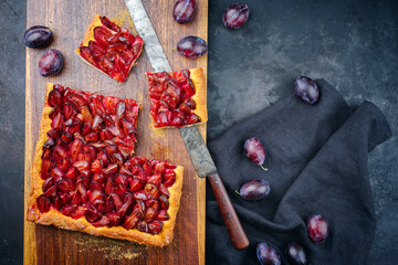 Traditional German Zwetschgenkuchen with sliced plums served as top view on a wooden design board