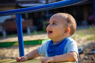 Fototapeta na wymiar Cute happy smiling baby boy walking at children playground outdoors