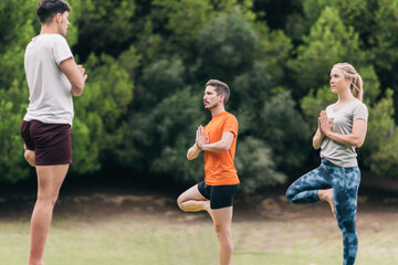 Three persons practising yoga in a park