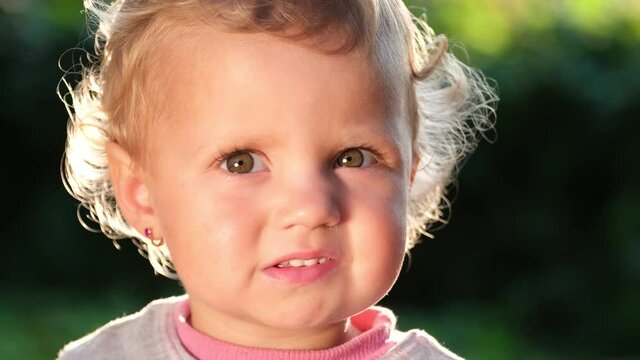 Beautiful face of a small European child, the sun illuminates her hair.