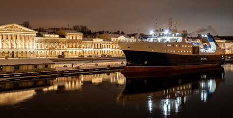 The panoramic footage of the winter night city Saint-Petersburg with picturesque reflection on water, big ship moored near Blagoveshchensky bridge or lieutenant Schmidt, Isaac cathedral on background