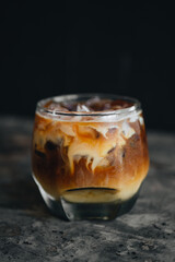 Iced coffee americano with milk in a glass at dark background