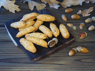Natural cookies, ripe oak fruits, acorns and yellow autumn leaves on a wooden table, top view, flat...