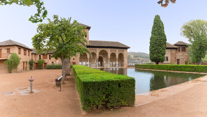 Fototapeta na wymiar View at the Partal Palace or Palacio del Partal , a palatial structure around gardens and water lake inside the Alhambra fortress complex located in Granada, Spain