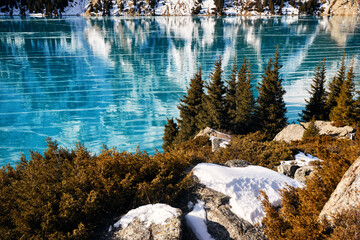 Winter lake with ice in the mountain forest