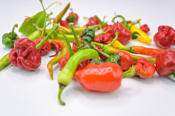 Close-up image of different color fresh hot peppers with leaf with white background