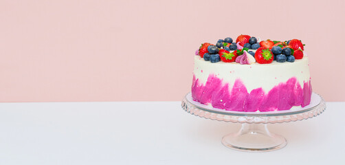 Delicate cake decorated with fresh berries, strawberries and blueberries on a light plain background