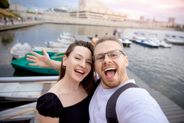 Fototapeta na wymiar Happy couple man and woman traveler makes selfie photo on background of catamarans parking sunlight. Concept Turkey travel walk on sea and lake