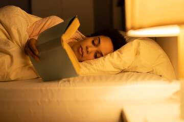 African American Woman Reading Book In Bed