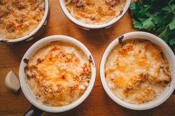 Julienne in portions, Mushrooms with cream and cheese casserole, Restaurant food on a dark background, Top view