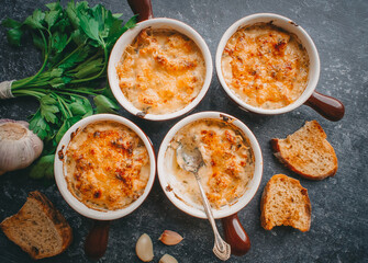 Julienne in portions, Mushrooms with cream and cheese casserole, Restaurant food on a dark background, Top view