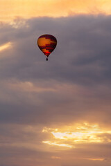 Orange and purple hot-air balloon flying in golden sunset sky. Balloon festival in Belgorod, Russia.