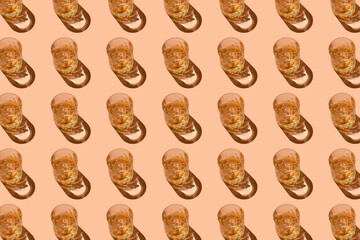 Pattern of strong alcohol drinks, hard liquors, spirits and distillates set in glasses with ice cubes: cognac, scotch, whiskey and other. Drink pattern on peach color background