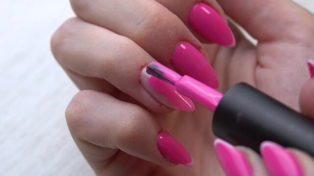 Selfmade manicure service. Manicurist paints nails with pink gel polish. Nail polish application. Manicured pink nails.