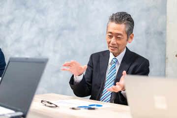 スーツで意見を述べる経営者